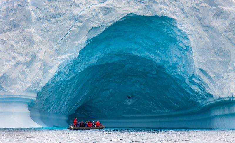 Small boat beneath an ice arch
