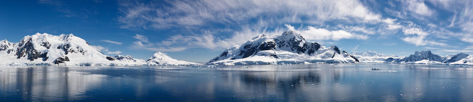 Panorama of glaciated Antarctic mountains across calm dark water